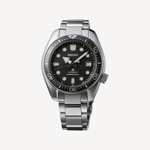 Eine Nahaufnahme einer automatischen Taucheruhr von Seiko, erhältlich bei Juwelier Morawitz in Düsseldorf. Sie verfügt über ein Edelstahlarmband, ein schwarzes Zifferblatt mit Leuchtmarkierungen, ein Datumsfenster bei 3 Uhr und ist bis zu 200 Meter wasserdicht. Die Lünette ist einseitig drehbar und mit Minutenmarkierungen versehen.