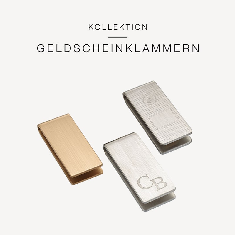 Vor weißem Hintergrund ist eine Sammlung von drei Geldscheinklammern aus Metall zu sehen. Sie tragen die Aufschrift „KOLLEKTION GELDSCHEINKLAMMERN“ von Juwelier Morawitz in Düsseldorf. Eine Klammer ist aus Gold, die anderen beiden aus Silber und weisen jeweils eine individuelle Gravur auf.
