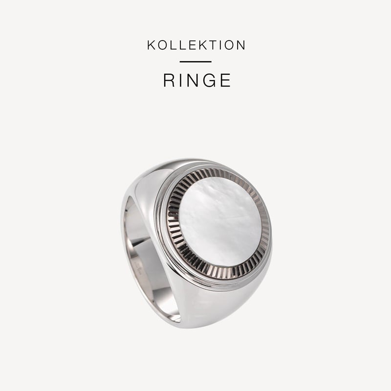 Ein Silberring mit einem runden, strukturierten, weißen Stein in der Mitte. Über dem Ring sind die deutschen Worte „KOLLEKTION RINGE“ auf einem schlichten weißen Hintergrund zu sehen, was die exquisite Handwerkskunst von Juwelier Morawitz in Düsseldorf hervorhebt.
