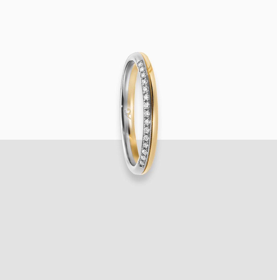 Juwelier-Morawitz-Schmucklexikon-alliancering Ein zweifarbiger Ring von Juwelier Morawitz in Düsseldorf mit einem eleganten Design mit einer goldenen Außenseite und einer silbernen Innenseite. Der Ring ist in der Mitte mit einer Reihe kleiner, funkelnder Diamanten verziert, die für einen anspruchsvollen und eleganten Look sorgen. Der Hintergrund ist ein einfacher Farbverlauf in Weiß und Grau.