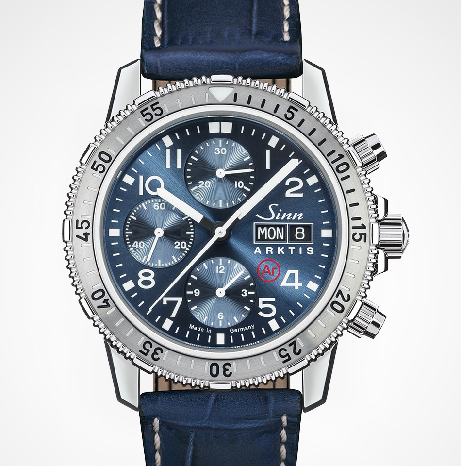 Juwelier-Morawitz-Uhrenlexikon-index-sinn Eine Sinn Arktis-Armbanduhr mit tiefblauem Zifferblatt, drei Hilfszifferblättern, Tag-/Datumsanzeige und silbernen Stundenmarkierungen. Sie verfügt über ein Edelstahlgehäuse und eine Lünette mit Minutenmarkierungen und ist mit einem blauen Lederarmband ausgestattet. Erhältlich bei Juwelier Morawitz in Düsseldorf. Der Markenname und das „Ar“-Logo befinden sich auf dem Zifferblatt.