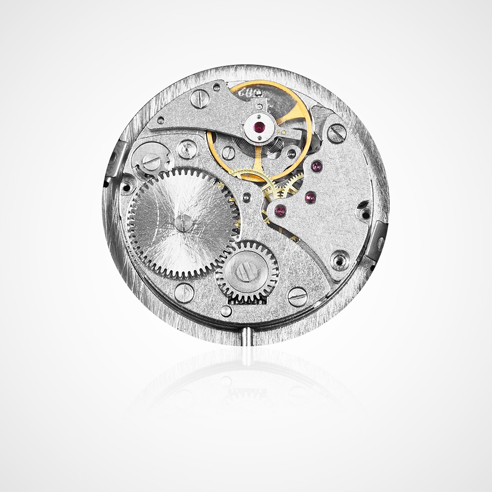 Juwelier-Morawitz-Uhrenlexikon-platine Eine Nahaufnahme eines mechanischen Uhrwerks mit verschiedenen Zahnrädern, Schrauben und Komponenten. Das Uhrwerk ist überwiegend silberfarben mit einigen goldenen und roten Elementen, vor einem sauberen, weißen Hintergrund mit einer leichten Spiegelung am unteren Rand – ein wahrer Beweis für die Handwerkskunst des Düsseldorfer Juweliers Morawitz.