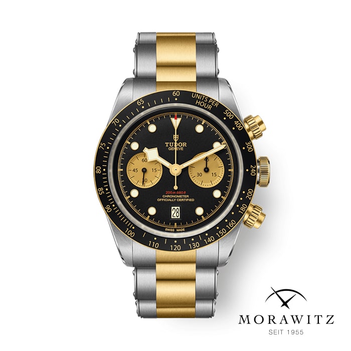 Eine luxuriöse Tudor-Chronographenuhr mit schwarzem Zifferblatt, zwei goldenen Hilfszifferblättern und einer Datumsanzeige auf der 6-Uhr-Position. Die Uhr verfügt über ein zweifarbiges Edelstahlarmband in Gold und Silber. Unten rechts sind das Morawitz-Logo und der Text „SEIT 1955“ zu sehen.