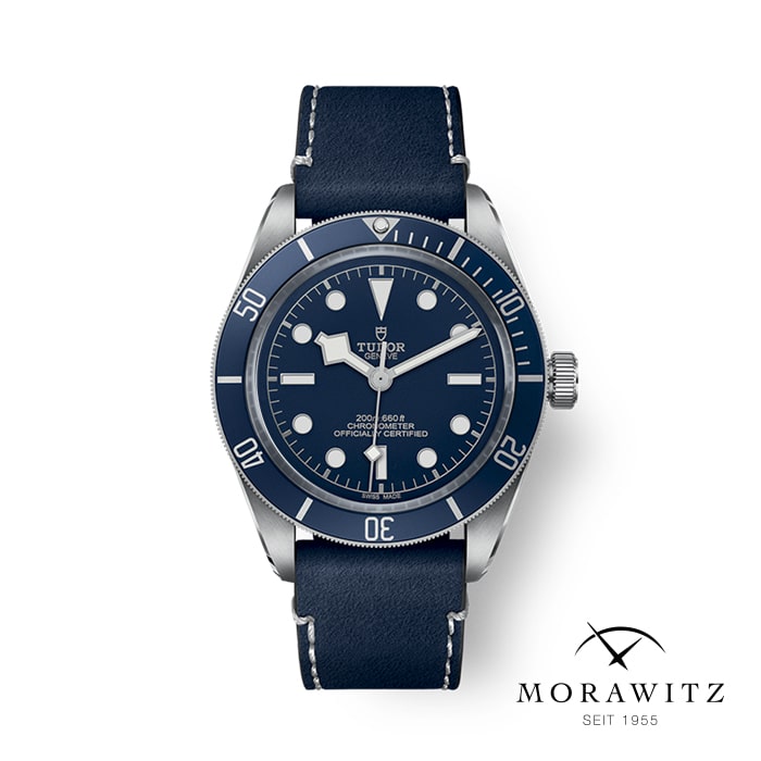 Eine blau-silberne Tudor-Armbanduhr mit rundem Zifferblatt, weißen Stundenmarkierungen und Zeigern. Die Uhr wird an einem blauen Lederarmband getragen. Der Hintergrund ist weiß mit dem Logo „Morawitz SEIT 1955“ in der unteren rechten Ecke.