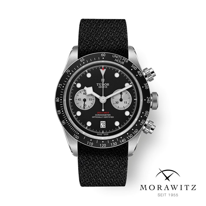 Eine elegante Tudor-Chronometer-Armbanduhr mit schwarzem Zifferblatt, drei Hilfszifferblättern und einem Datumsfenster bei 6 Uhr. Die Uhr hat ein schwarzes strukturiertes Armband. Das Morawitz-Logo mit dem Text „Seit 1955“ befindet sich in der unteren rechten Ecke.