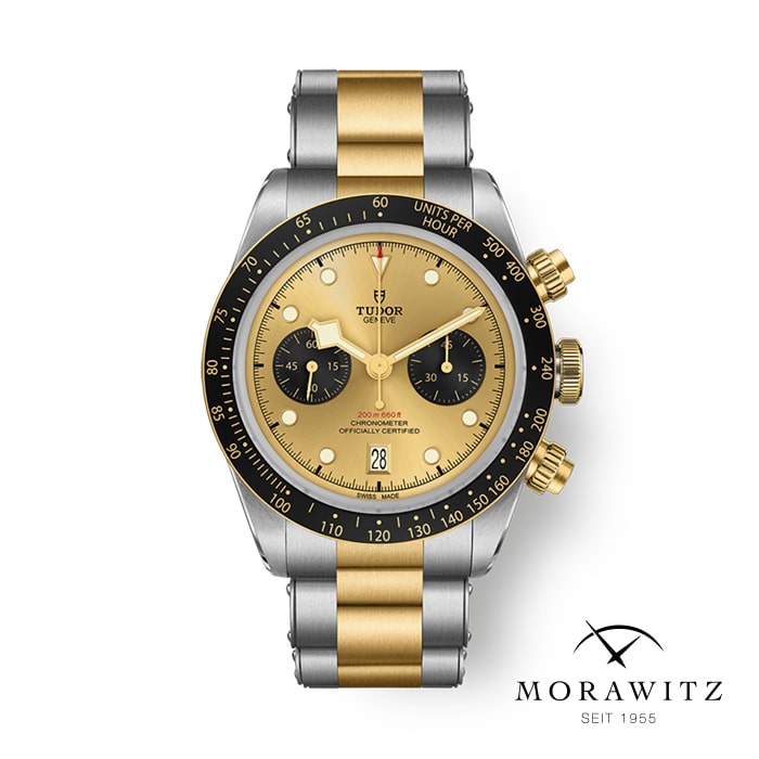 Eine Luxusarmbanduhr mit einem silber- und goldfarbenen Metallarmband. Das Zifferblatt ist goldfarben mit schwarzen Akzenten und verfügt über drei Hilfszifferblätter, mehrere Anzeigen und Texte, darunter „Tudor“ und „Chrono“. In der unteren Ecke sind das Logo und der Text „Morawitz seit 1955“ zu sehen.