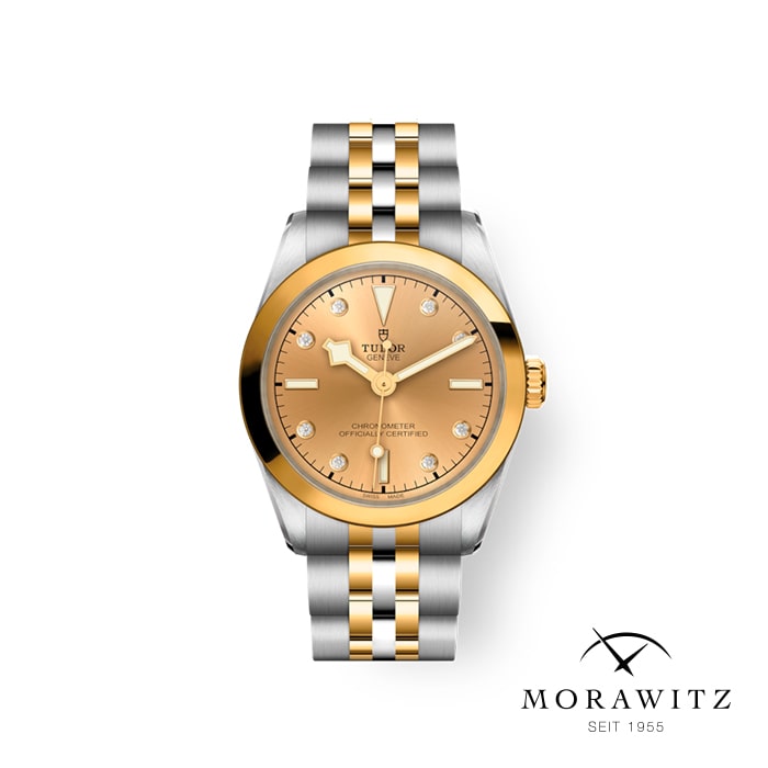 Eine zweifarbige Armbanduhr mit einem goldenen und silbernen Metallarmband, einer runden Lünette und einem hellbraunen Zifferblatt mit Diamant-Stundenmarkierungen. Auf dem Zifferblatt sind die Marke „Tudor“ und das Logo abgebildet. Unten rechts sind das Logo und der Name „Morawitz“ mit „Seit 1955“ aufgedruckt.