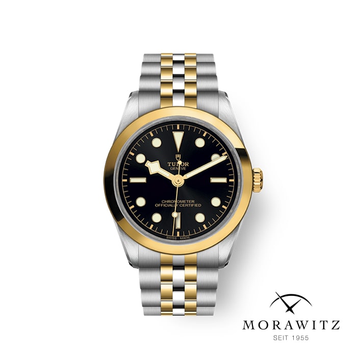 Eine Luxusarmbanduhr mit schwarzem Zifferblatt, goldenen Stundenmarkierungen und zweifarbigem Metallarmband aus Gold und Silber. Auf dem Zifferblatt ist der Markenname „Tudor“ zu sehen. Das Logo für „Morawitz Seit 1955“ befindet sich in der unteren rechten Ecke.