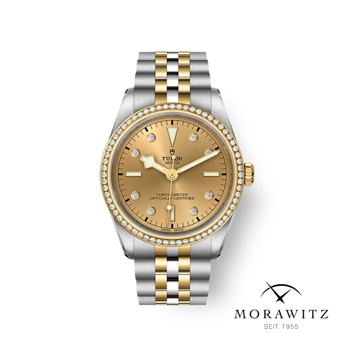 Eine Luxusarmbanduhr mit einem zweifarbigen Metallarmband in Gold und Silber, einem goldenen Zifferblatt und Diamant-Stundenmarkierungen. Der Markenname „Tudor“ ist auf dem Zifferblatt zu sehen. Das „Morawitz“-Logo mit dem Text „SEIT 1955“ befindet sich unten rechts im Bild.