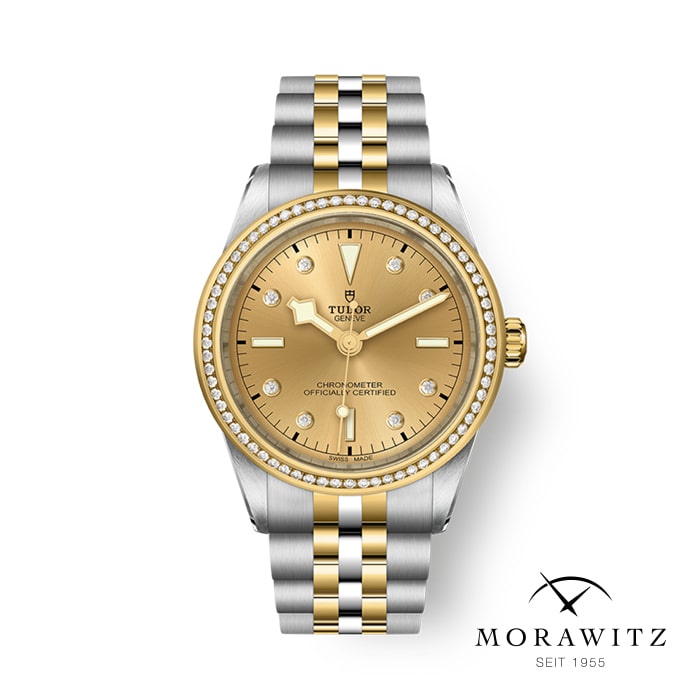 Eine Luxusarmbanduhr mit einem Armband aus gold- und silberfarbenem Edelstahl, einem goldfarbenen Zifferblatt, Diamantmarkierungen und dem „Tudor“-Branding. Die Uhr hat eine strukturierte Lünette, die mit Diamanten verziert ist. Unten rechts ist das Markenlogo „Morawitz Seit 1955“ abgebildet.