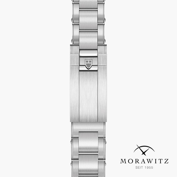 Eine Nahaufnahme des silbernen Metallarmbands der TUDOR BLACK BAY CHRONO zeigt eine Schließe mit einem Wappenemblem. Das Morawitz-Logo und der Schriftzug "Seit 1955" erscheinen in der rechten unteren Ecke.