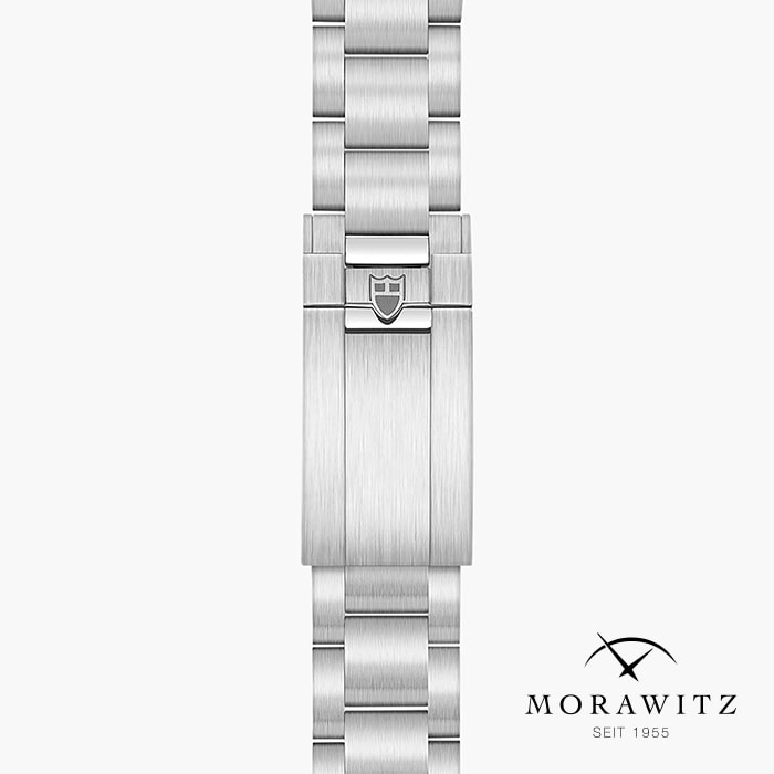 Nahaufnahme des silbernen Metallarmbands TUDOR BLACK BAY 68 mit einer Schließe, die ein Schildlogo trägt. Auf dem weißen Hintergrund sind das Morawitz-Logo und unten rechts der Text "Morawitz Seit 1955" zu sehen.