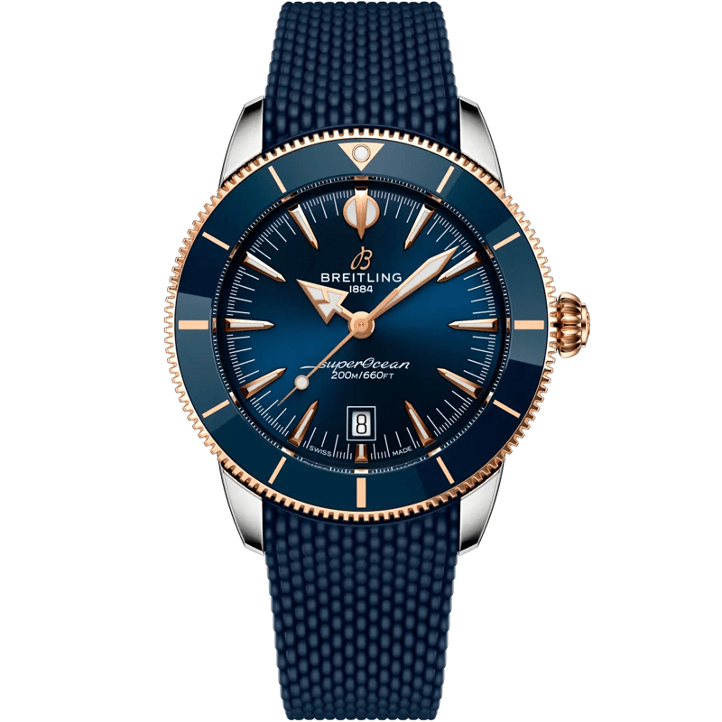 Juwelier-Morawitz-Breitling-Superocean-Heritage-ub3112161c1s1 Eine Breitling Superocean Heritage Armbanduhr mit blauem strukturiertem Armband, blauem Zifferblatt, goldener Lünette und goldener Krone. Die Uhr zeigt das Datum und die Aufschrift "SuperOcean 200m/660ft" auf dem Zifferblatt.